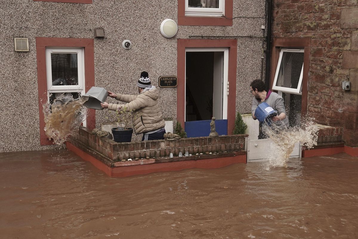 Men try to control the flow of flood water, outside a property, in Appleby-in-Westmorland, as Storm Ciara hits the UK, in Cumbria, England, Sunday Feb. 9, 2020. Trains, flights and ferries have been cancelled and weather warnings issued across the United Kingdom as a storm with hurricane-force winds up to 80 mph (129 kph) batters the region. (Owen Humphreys / AP)