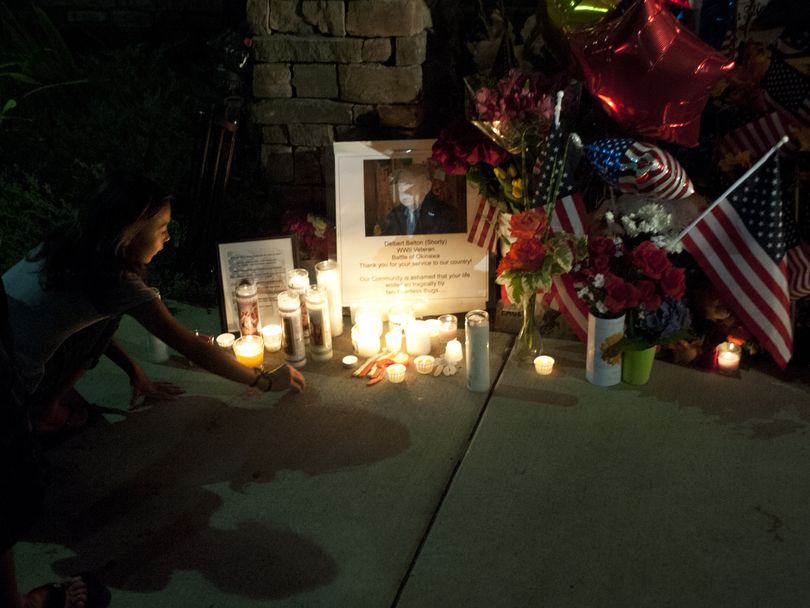 Delaina Duran, 10, of Spokane, places a ring she made of Play-Doh on a memorial erected in memory of Delbert Belton during a vigil on Friday at the Eagles Lodge. (Tyler Tjomsland)