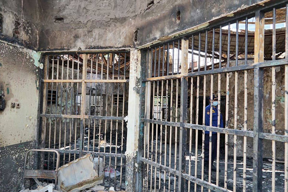 In this photo released by Indonesian Ministry of Justice and Human Rights, a fireman stands inside a charred cell after a fire at Tangerang Prison in Tangerang, Indonesia, Wednesday, Sept. 8, 2021. A massive fire raged through the overcrowded prison near Indonesia