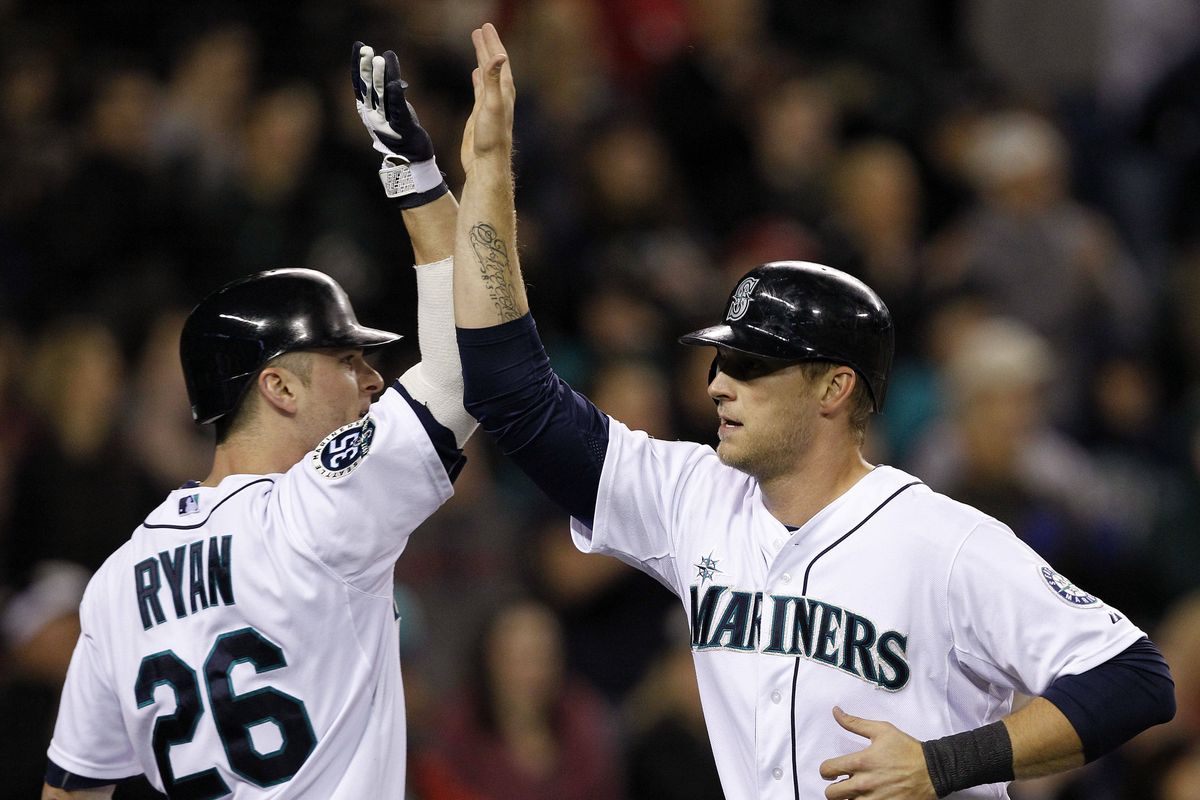 Brendan Ryan congratulates Michael Saunders after Saunders scored what ended up being the winning run in the eighth inning. (Associated Press)