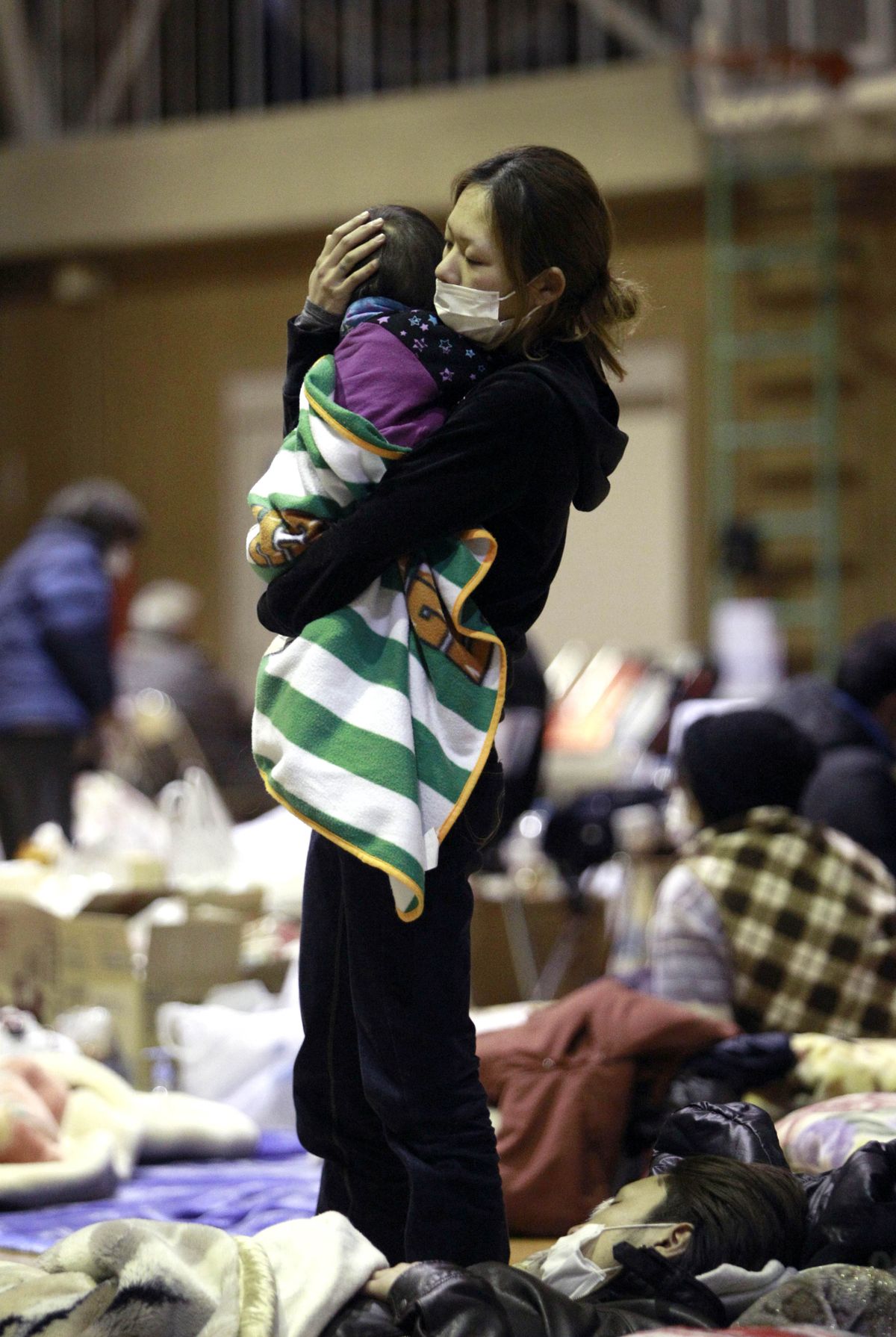A woman holds her child at a shelter after being evacuated from areas around the Fukushima nuclear facilities damaged by last week