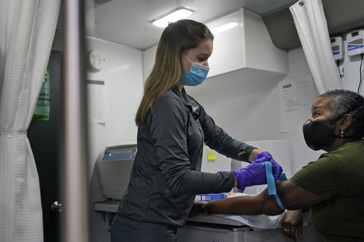 Nurse Brianne Stockman, left, prepares to draw some blood from study participant Lani Muller on Tuesday in a mobile medical unit parked in the Queens borough of New York.  (Seth Wenig)