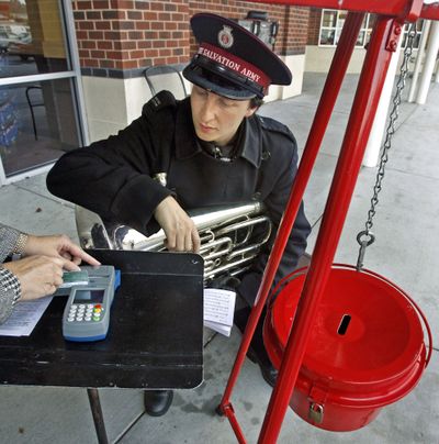 Matt Sims, bandmaster for the Salvation Army, talks a donor through a credit card donation at the kettle he was manning at the Forest Hill Ukrop’s in Richmond, Va.  (Associated Press)