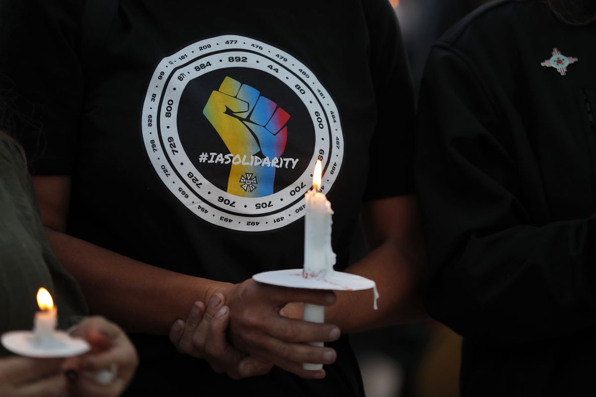 Movie industry worker Hailey Josselyn, wearing a T-shirt of the International Alliance of Theatrical Stage Employees (IATSA), holds a candle during a vigil to honor cinematographer Halyna Hutchins in Albuquerque, N.M., on Oct. 23, 2021. Hutchins was fatally shot on Thursday, Oct. 21, after an assistant director unwittingly handed actor Alec Baldwin a loaded weapon and told him it was safe to use on the set of a Western filmed in Santa Fe, N.M. Members of the IATSA,will vote on a proposed three-year union contract with Hollywood producers. (Andres Leighton)