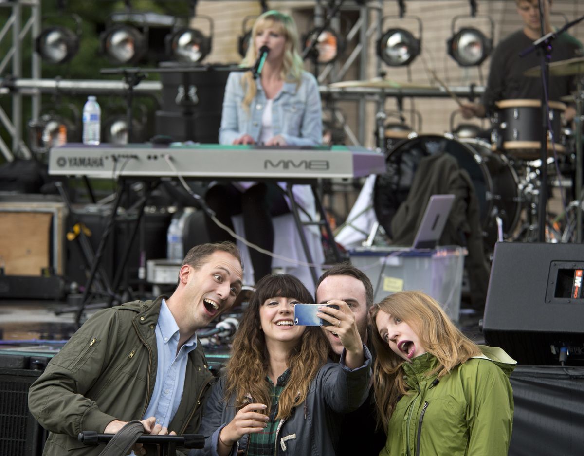 Max Harnishfeger, Karli Ingersoll, Caleb Ingersoll and Carrie Harnishfeger gather for a picture as Cami Bradley, top center, and her band perform a sound check in Riverfront Park on Thursday. The four are members of the band Cathedral Pearls and were waiting for their sound check. The musicians performed Thursday evening as part of Hoopfest. (Dan Pelle)