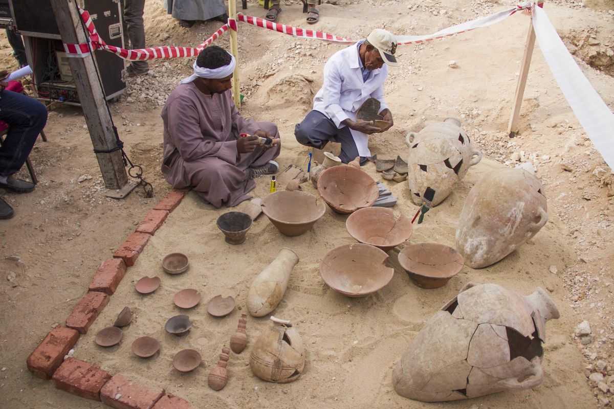 Egyptian excavation workers restore pottery near a new found  tomb in Draa Abul Naga necropolis on Luxor’s West Bank known as “KAMPP 161” during an announcement Saturday, Dec. 9, 2017, for the Egyptian Ministry of antiquities about new discoveries in Luxor, Egypt. Egypt’s Antiquities Ministry says archaeologists have discovered two ancient tombs in the southern city of Luxor. The ministry said Saturday that one tomb has five entrances leading to a rectangular hall, and contains painted wooden funerary masks, clay vessels and a mummy wrapped in linen. (Hamada Elrasam / Associated Press)