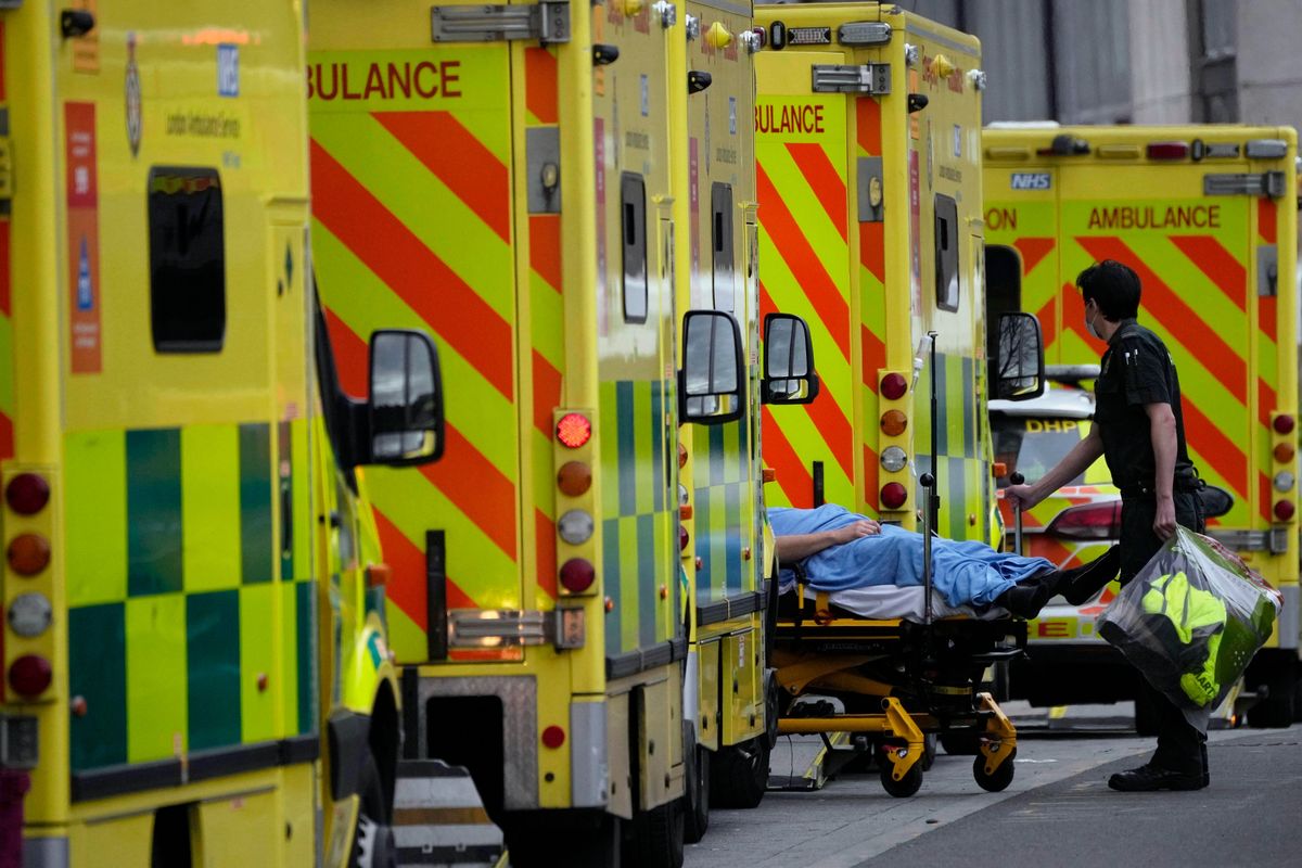 FILE - A patient is pushed on a trolley after arriving in an ambulance outside the Royal London Hospital in the Whitechapel area of east London, Jan. 6, 2022. Scientists are seeing signals that COVID-19′s alarming omicron wave may have peaked in Britain and is about to do the same in the U.S., at which point cases may start dropping off dramatically.  (Matt Dunham)