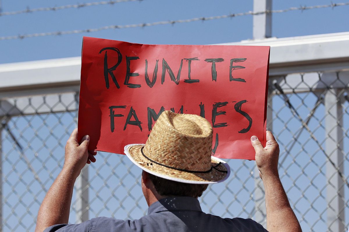 A protester holds a sign outside a closed gate at the Port of Entry facility, Thursday, June 21, 2018, in Fabens, Texas, where tent shelters are being used to house separated family members. President Donald Trump