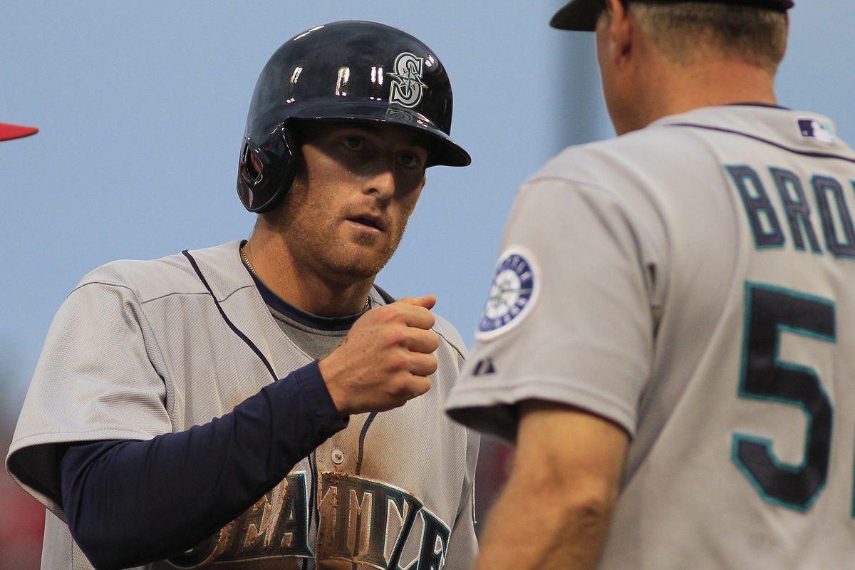 Mariners shortstop Brad Miller is congratulated by coach Daren Brown after hitting his second triple of the game. (Associated Press)
