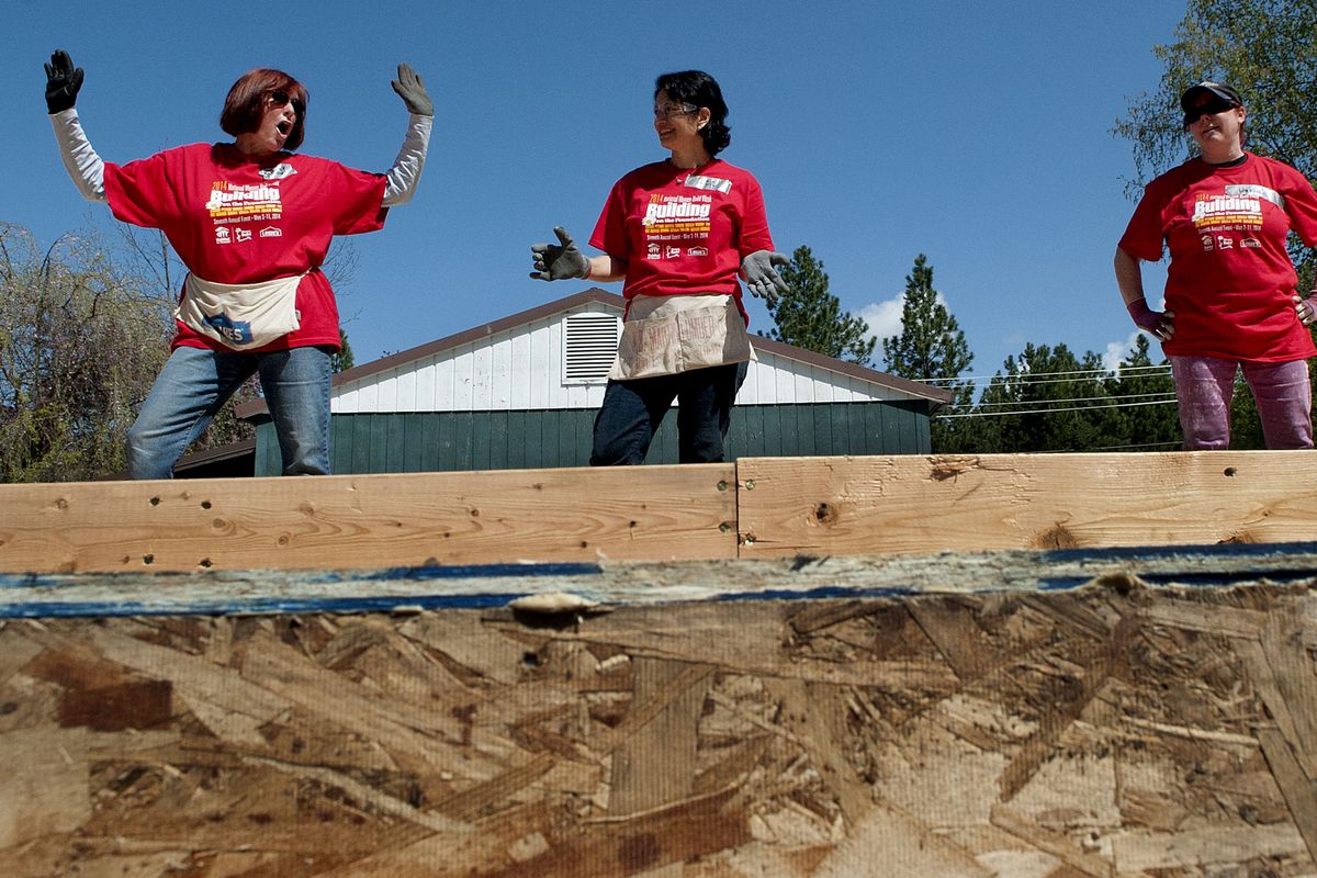 Trudy Elliott, left, does the “raise the wall” dance along with Lea Williams, center, and Heather Barker as they prepare to help lift a framed wall during Habitat for Humanity National Women Build Week in Coeur d’Alene on Wednesday. (Kathy Plonka)