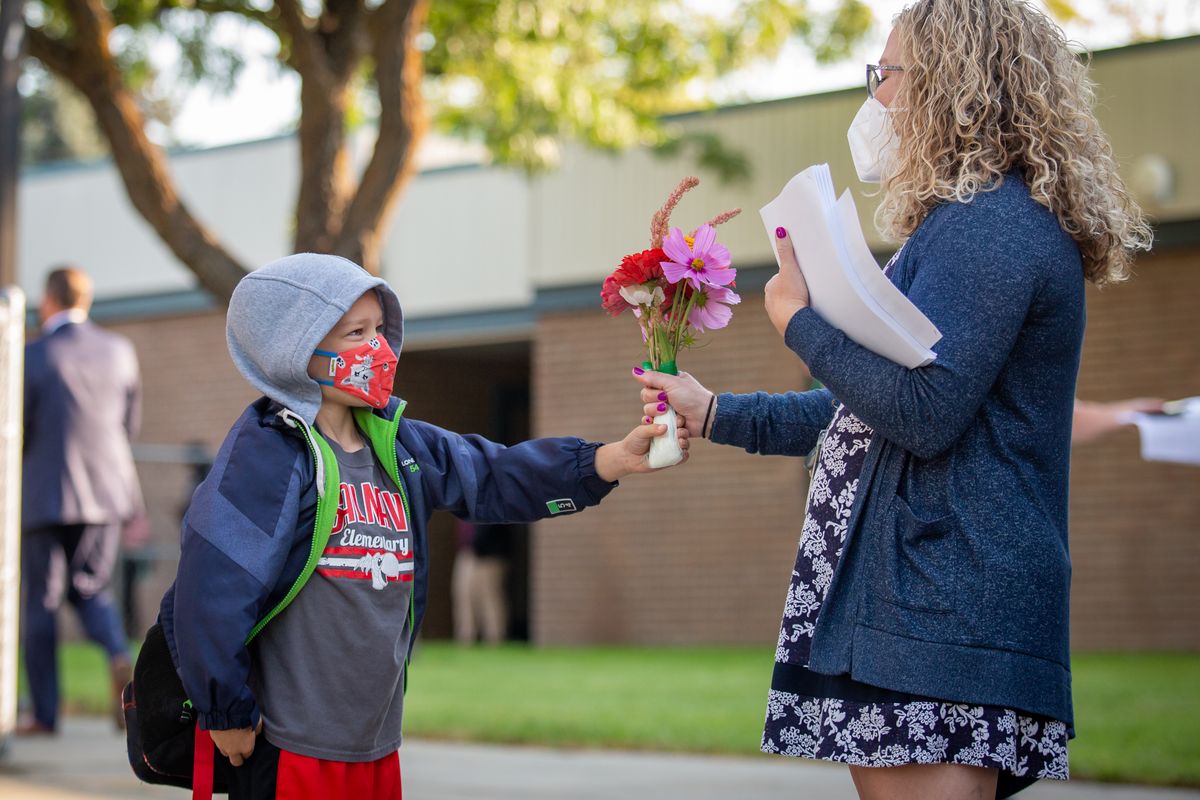 Second-grader Clayton Kenison gives Principal Celina Brennan a bouquet of flowers for the first day of the 2021-22 school year at Salnave Elementary School on Wednesday. Students are masked and in-person for classroom learning in the Cheney Public School District.  (Libby Kamrowski/THE SPOKESMAN-REVIEW)