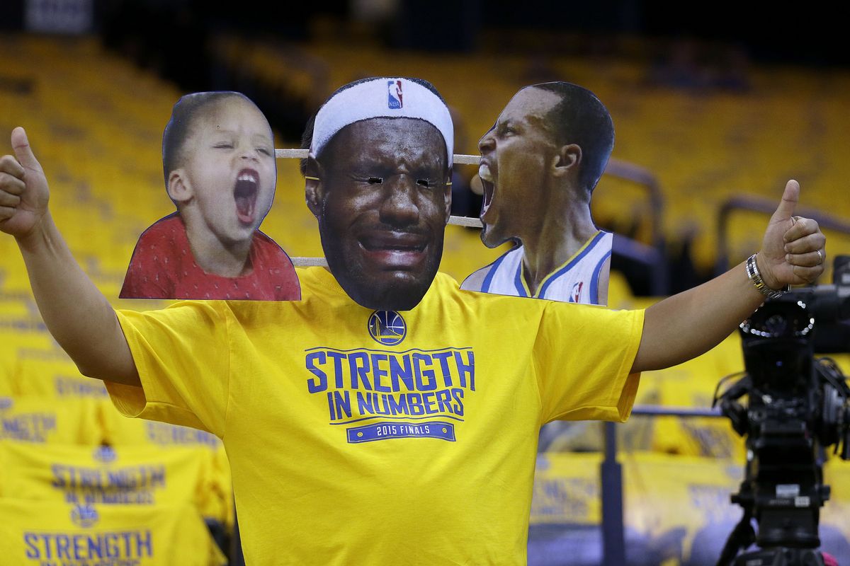 A Golden State Warriors fan wears a mask of Cleveland Cavaliers forward LeBron James, center, with photos of Golden State Warriors guard Stephen Curry, right, and Curry
