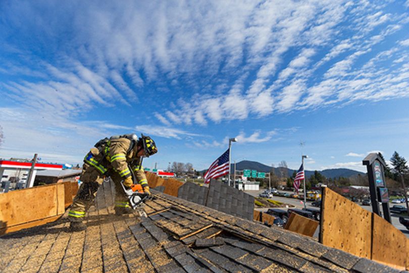 Josh Sutherland, a firefighter with the Coeur d���Alene Fire Department, cuts a hole in the roof of the former showroom of Dave Smith Frontier Leasing and Sales during a training exercise Monday at the Coeur d���Alene dealership. (Shawn Gust/press)