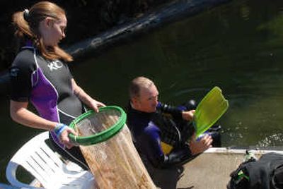 
Kymberly Bowlby, left, helps  Doug Freeland with his equipment while the two were on their way to a dive to survey Spirit Lake for milfoil. 
 (JESSE TINSLEY Photos / The Spokesman-Review)