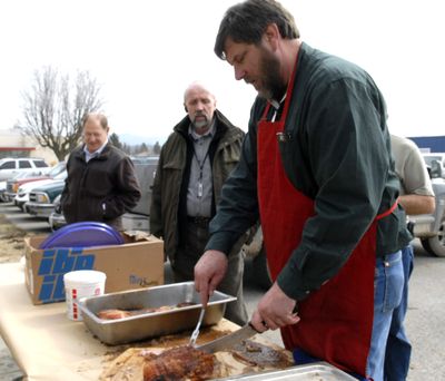 East Valley superintendent John Glenewinkel cuts meat March 19, that he smoked for the transportation and maintainence employees in appreciation for their extra effort and hard work during December and January storms.  (J. BART RAYNIAK / The Spokesman-Review)