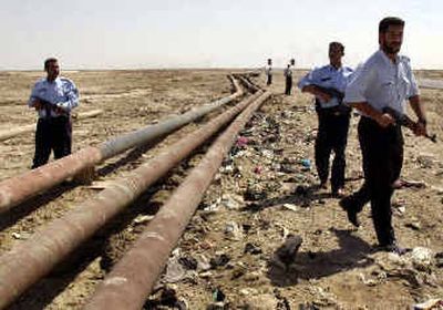 
Iraqi police patrol along oil pipelines outside the town of Faw on Wednesday. Saboteurs blasted a key pipeline Wednesday for the second time in as many days, halting Iraq's oil exports, officials said. 
 (Associated Press / The Spokesman-Review)