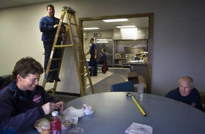 
Lt. Darci Frasier, left, jokes with Lt. Scott Himelspach, right, and firefighter D.J. Hill while they move into the remodeled Spokane Fire Station 1  Friday. The station now has bathroom facilities for female firefighters that are as large as those for the men.
 (Holly Pickett / The Spokesman-Review)