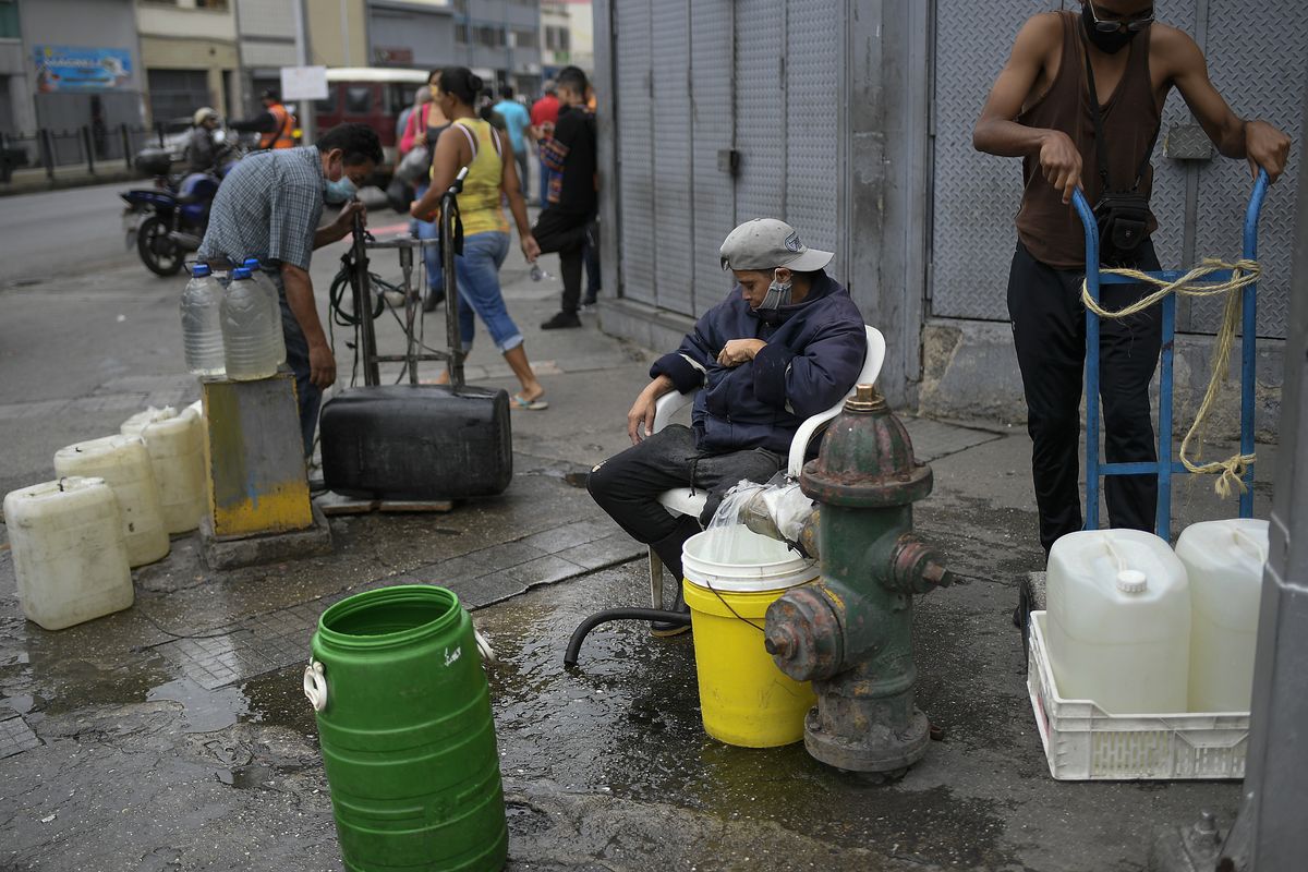 Residents tap into a fire hydrant to fill their containers with water in the San Juan neighborhood of Caracas, Venezuela, Tuesday, Jan. 19, 2021, amid the new coronavirus pandemic. Venezuela