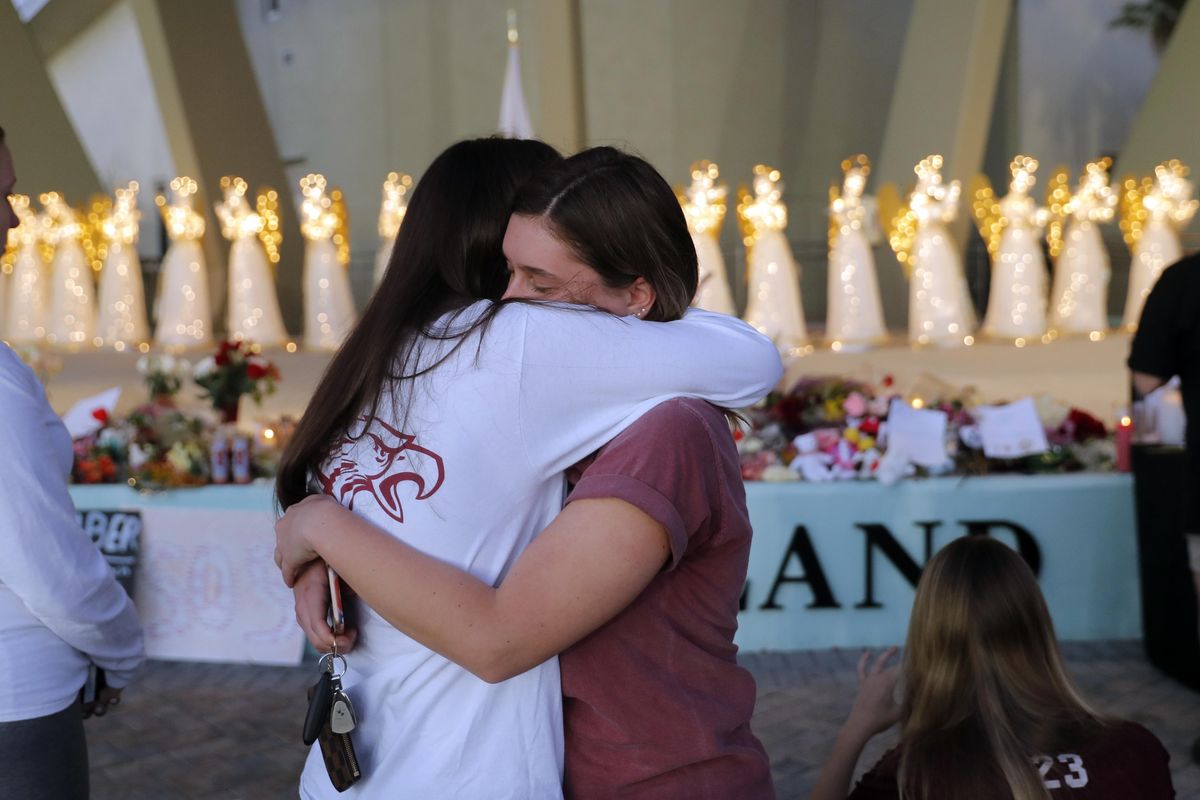 People hug at a public memorial for the 17 deceased students and faculty from Wednesday