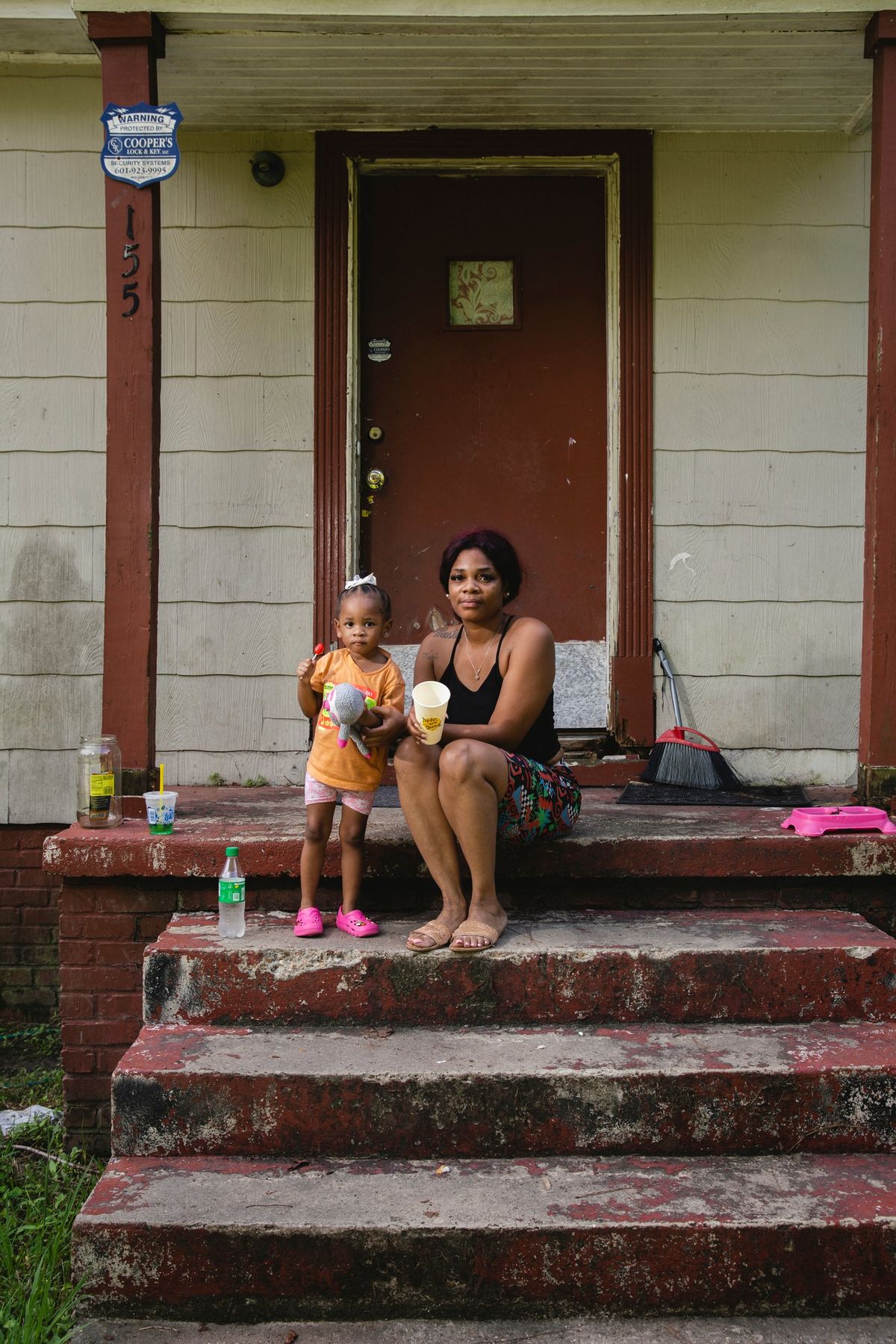 Roshonda Snell and her 2-year-old daughter sit on their stoop in the house they have been renting for the past three years in South Jackson, Miss. MUST CREDIT: Photo for The Washington Post by Camille Lenain. (Camille Lenain/For The Washington Post)