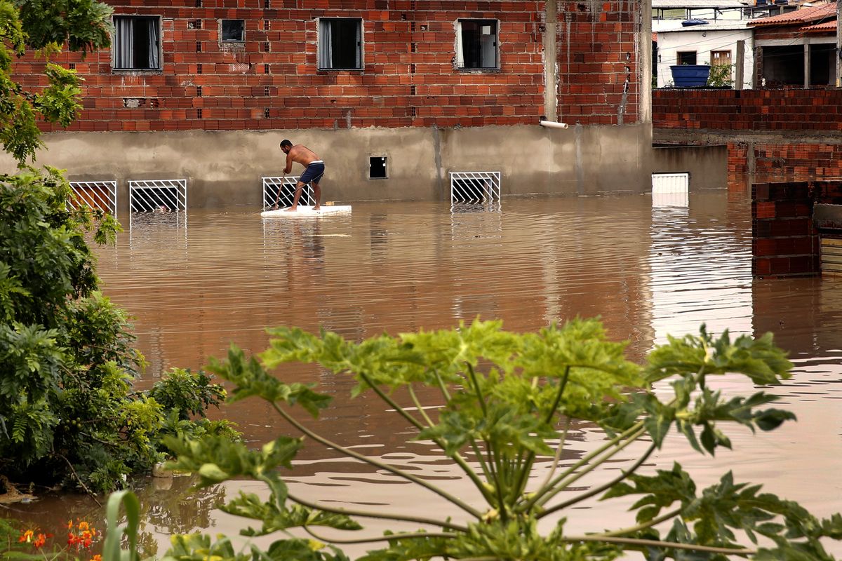 A man tries to recover furniture through the window of his house due to flooding caused by intense rains in the city of Itapetinga, in the southern region of the state of Bahia, Brazil, Sunday, Dec. 26, 2021. The Bahia state government