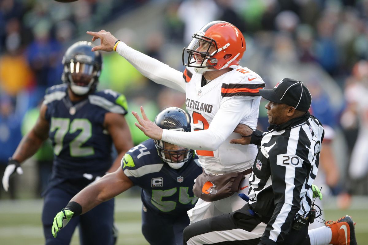 Umpire Barry Anderson is knocked down as Browns’ Johnny Manziel (2) gets a pass off as Seattle’s Bobby Wagner (54) puts on pressure. (Scott Eklund / Fr171040 Ap)
