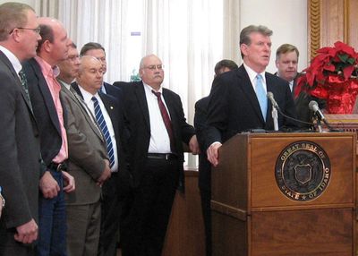 Flanked by legislators and state officials, Gov. Butch Otter announces more state budget cuts Monday in Boise. The only exception will be for public schools.  (BETSY Z. RUSSELL / The Spokesman-Review)