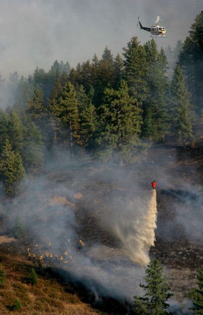 
A helicopter drops water near a crew trying to keep a wildfire from reaching a nearby home in Pataha Creek, south of Pomeroy, Wash., on Aug. 8.
 (Christopher Onstott / The Spokesman-Review)