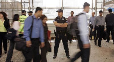 
Port Authority Police Officer Milt Fong stands watch as commuters leave the World Trade Center PATH station Friday. 
 (Associated Press / The Spokesman-Review)