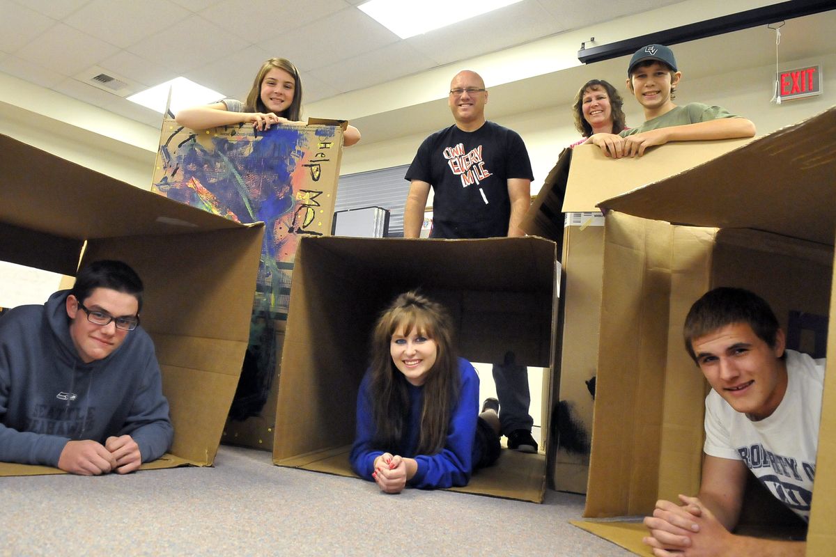 Youth group members and parents, from left, Ryan McCauley, 16, Lauren McCauley, 13, Katrina Boik, 18, Doug Wanner, Meta Boik, Darren Boik, 14, and Josh Wanner, 17, plan to spend Friday night out in these cardboard boxes they decorated on Monday. (Jesse Tinsley)