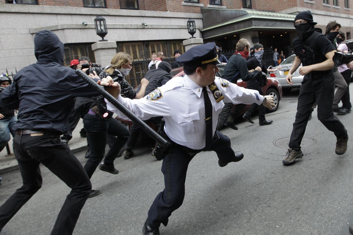 A police lieutenant swings his baton at an Occupy Wall Street activists on Tuesday in New York. Hundreds of activists with a variety of causes spread out across the city. (Associated Press)