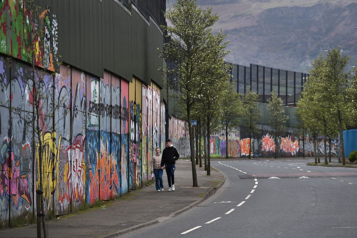 A couple walk along the so called Peace Wall on Apr. 3, 2023, in Belfast, Northern Ireland. The Good Friday Agreement, signed on April 10, 1998, ended most of the violence during the decades-long conflict known as The Troubles. The Peace Walls protect the communities from attacks from one another, some have been removed but in some instances other walls have become higher and longer since the Good Friday Agreement.   (Charles McQuillan/Getty Images North America/TNS)