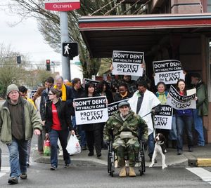 OLYMPIA -- Protesters who support the Affordable Care Act march through downtown on their way to the offices of Attorney General Rob McKenna, who is part of a lawsuit to overturn it. (Jim Camden)