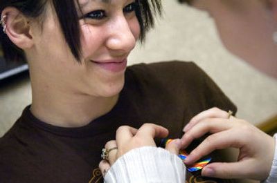 
Causha Morehead, 16, gets help attaching a rainbow ribbon to her shirt to show observance of a day of silence at Lewis and Clark High School on Wednesday. By not speaking, participants protested the bullying and harassment of gay and lesbian high school and middle school students. 
 (Holly Pickett / The Spokesman-Review)