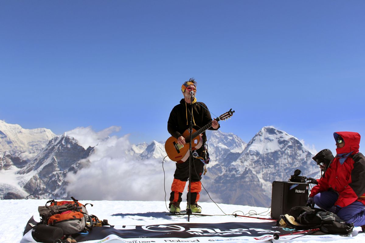 In this May 16 photo released by Music4Children, a musician performs atop a Himalayan peak. (Associated Press)