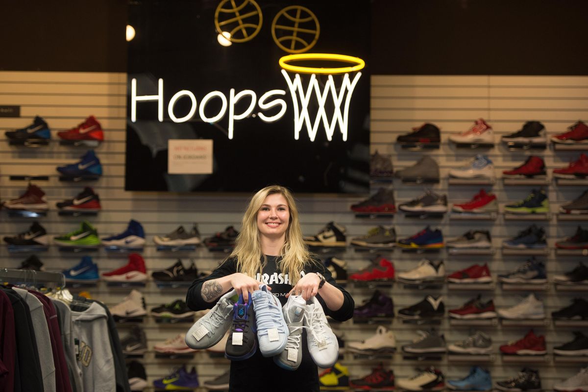 Mikaela Pilant poses for a photo with a selection of Hoopfest exclusive shoes she will be selling during Hoopfest on Thursday at Sport Town in Spokane. (Tyler Tjomsland / The Spokesman-Review)