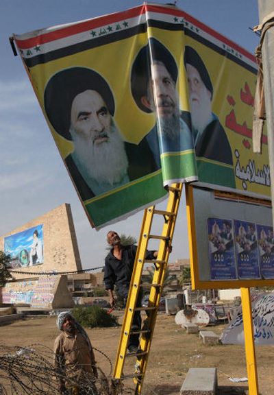 
On Saturday, two Iraqi municipality workers in Baghdad remove an election campaign poster for the Shiite-led  United Iraqi Alliance. 
 (Associated Press / The Spokesman-Review)