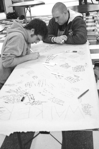 
Emmett High School seniors Kyle Blaser, left, and Matt Moen write their condolences on a sheet to be given to the family of some of the students killed in Tuesday's fatal car crash on Wednesday. A car carrying five children on their way to school slid off an icy highway into a pond on Tuesday. 
 (MIKE VOGT Associated Press / The Spokesman-Review)