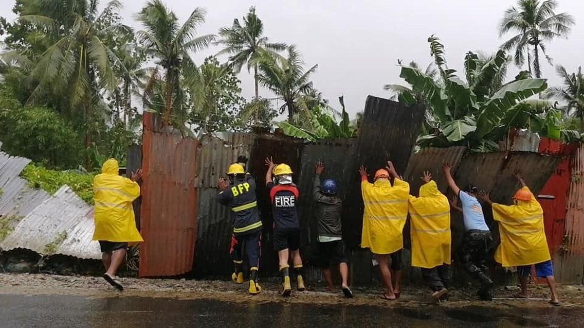 In this photo provided by the San Policarpo Firestation, firemen and police push up a steel fence as they clear roads during rain caused by Typhoon Surigae in the municipality of San Policarpo, Eastern Samar, eastern Philippines on Sunday April 18, 2021. An approaching typhoon has left at least one person dead, another missing and prompted the evacuation of more than 100,000 people as a precaution in the eastern and central Philippines, although the unusual summer storm is not expected to blow into land, officials said Monday.  (FO1 Marianne Jabinal)
