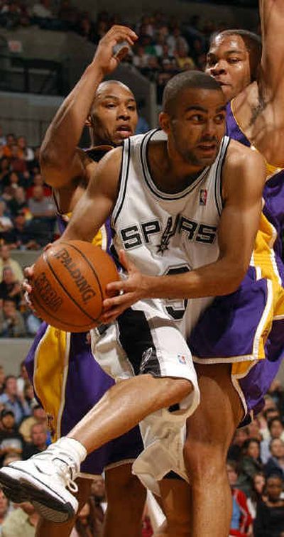 
San Antonio Spurs' point guard Tony Parker looks for room between Los Angeles Lakers' Caron Butler, left, and Devean George during their game on Saturday.
 (Associated Press / The Spokesman-Review)