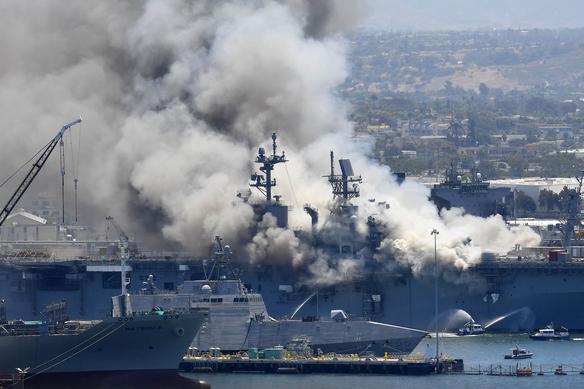 FILE - In this July 12, 2020, file photo, smoke rises from the USS Bonhomme Richard in San Diego after an explosion and fire on board the ship at Naval Base San Diego. The U.S. Navy said Thursday, July 29, 2021, that charges have been filed against a sailor who is accused of starting a fire last year that destroyed a warship docked off San Diego. The amphibious assault ship called the USS Bonhomme Richard burned for more than four days and was the Navy