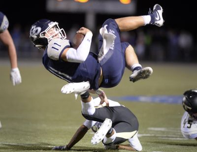 Gonzaga Prep QB Liam Bell looks for a place to land after vaulting over a defender on the keeper play, Friday, Oct. 9, 2015, at Gonzaga Prep's field. (Jesse Tinsley / The Spokesman-Review)