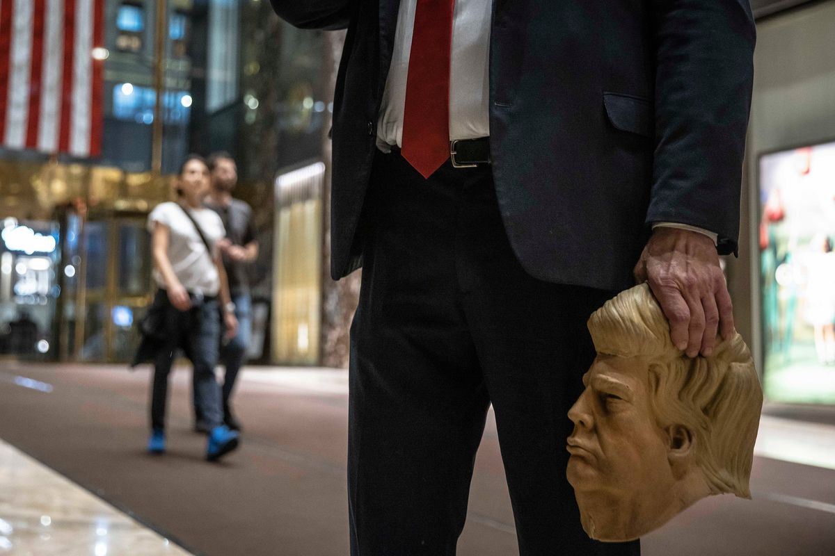 A man holds a mask of former President Donald Trump inside Trump Tower in New York on Sunday, Oct. 1, 2023, ahead of Trump