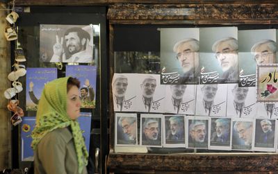 An Iranian woman walks Thursday past campaign posters of leading challenger and reformist candidate Mir-Hossein Mousavi, posters at right, and current president Mahmoud Ahmadinejad, at top left, in Tehran.  (Associated Press / The Spokesman-Review)