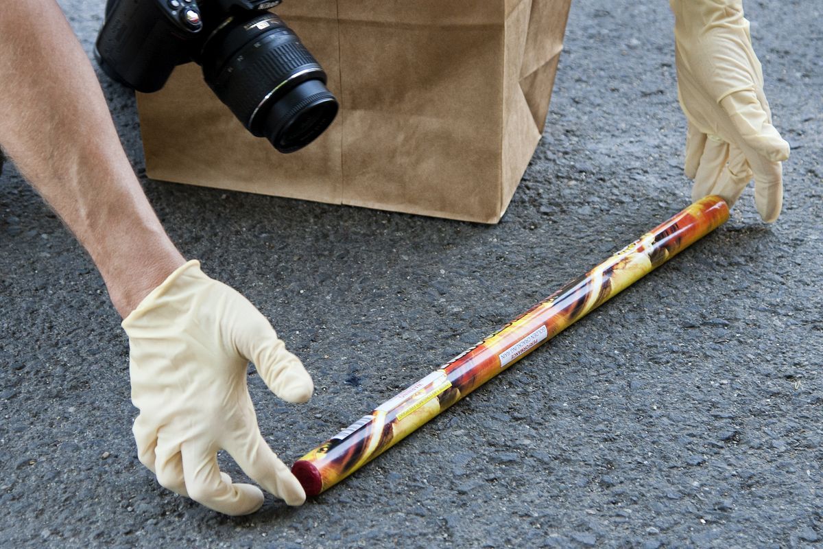 A Spokane Fire Department fire investigator collects a Roman candle for evidence at a house fire at the corner of Broadway and Chestnut on Friday. (Dan Pelle)