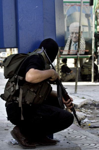 
Members of the new security force of the Hamas-led government take cover Monday near a poster of Palestinian President Mahmoud Abbas in Gaza City
 (Associated Press / The Spokesman-Review)