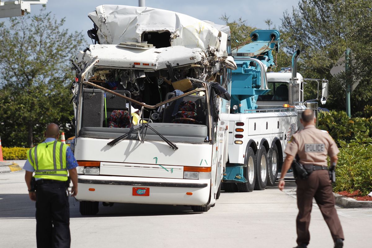 Law enforcement officers watch as a bus which hit a concrete overpass at Miami International Airport is hauled away, Saturday, Dec. 1, 2012 in Miami. The vehicle was too tall for the 8-foot-6-inch entrance to the arrivals area, and buses are supposed to go through the departures area which has a higher ceiling, according to an airport spokesperson. (Wilfredo Lee / Associated Press)