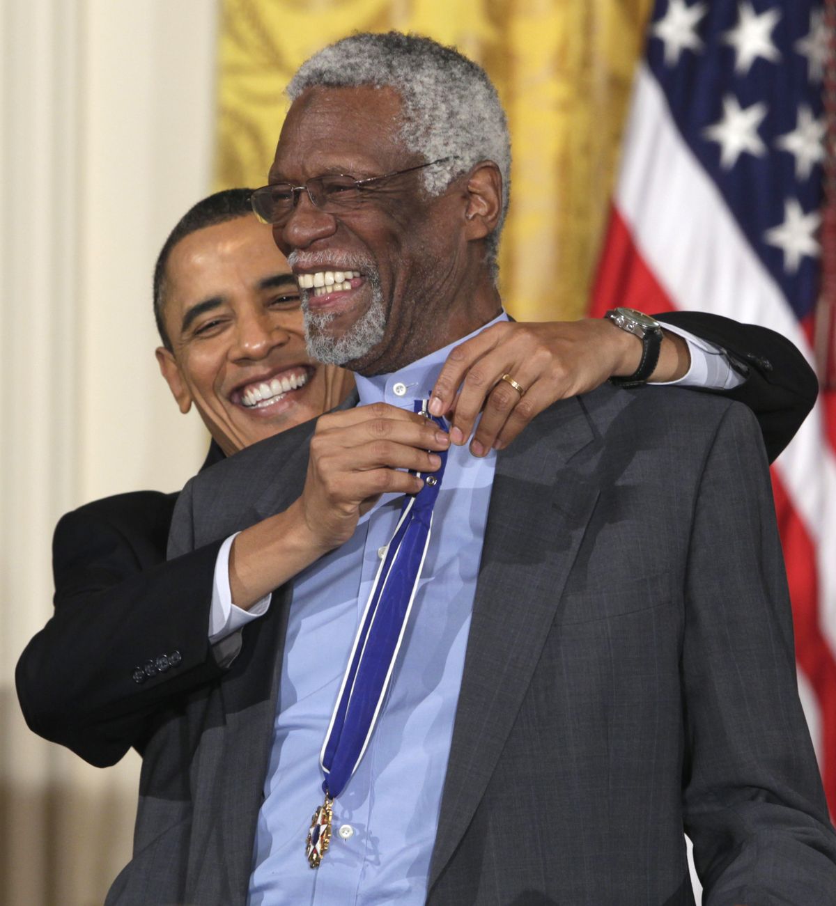 President Barack Obama reaches up to present a 2010 Presidential Medal of Freedom to basketball hall of fame member and former Boston Celtics coach and captain Bill Russell, Tuesday, Feb. 15, 2011, during a ceremony in the East Room of the White House in Washington. (Carolyn Kaster / Associated Press)