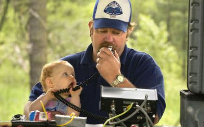 Tom Rose of the Spokane County Amateur Radio Emergency Service holds his 9-month-old daughter, Shelby, as he tries to make contact with a radio operator in San Francisco, Saturday afternoon in Valleyford County Park.
(Dan Pelle / The Spokesman-Review)