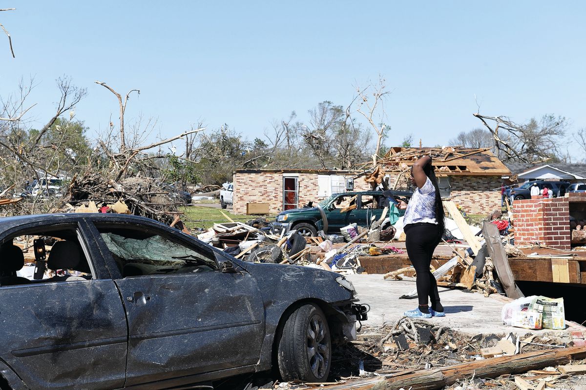 Above: Kenterica Sardin, 23, stands where her bedroom once was and home once stood on Saturday after a series of powerful storms and at least one tornado in Rolling Fork, Miss. Left: A vehicle is impaled by debris on Saturday in Rolling Fork, Miss.  (Will Newton)